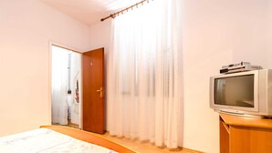 Una habitación de hotel con una cama, un aparador de madera, un televisor y una puerta con un número.