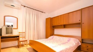 Un dormitorio con cama, un escritorio de madera con televisor, una silla y un armario.