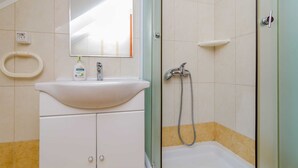 A bathroom with a white sink, a mirror, a toilet, and a shower area.