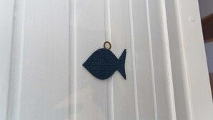 Un ornement bleu en forme de poisson est suspendu à une porte blanche.