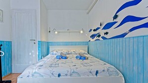 Une chambre à coucher comprenant un lit, un luminaire fixé au mur et un élément décoratif mural.