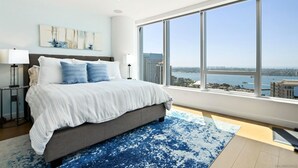 A modern bedroom with a large bed, a view of the city, and a cityscape through the window.