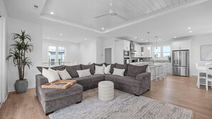 A spacious living area with a sectional sofa, a large rug, and a potted plant. - Luxe 4 Bedroom Home w/ Ocean views & Quick Private Beach Access in Surf City! (Surf City)