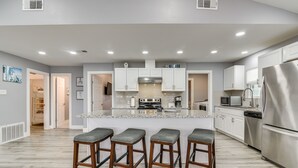A modern kitchen with a central island, stainless steel appliances, and a bar stool seating area. - Modern Freeport Home w/ Views: Walk to Beach! (Freeport)