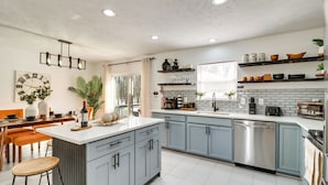 Una cucina moderna con mobili grigi, un piano di lavoro bianco ed elettrodomestici in acciaio inossidabile.