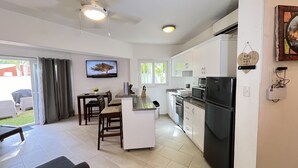 Una cocina moderna con armarios blancos, un refrigerador negro y un comedor con mesa y sillas.