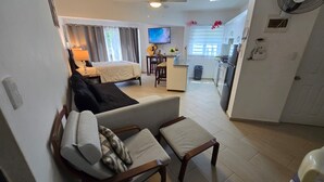 Un espacio habitable compacto con sofá, cama, comedor y kitchenette.