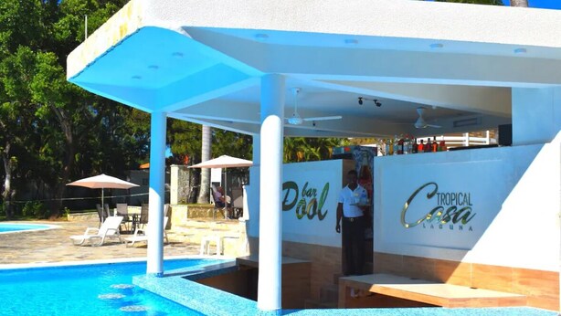 Zona de bar junto a la piscina, con un letrero que dice "Dool Tropical Casa Laguna".