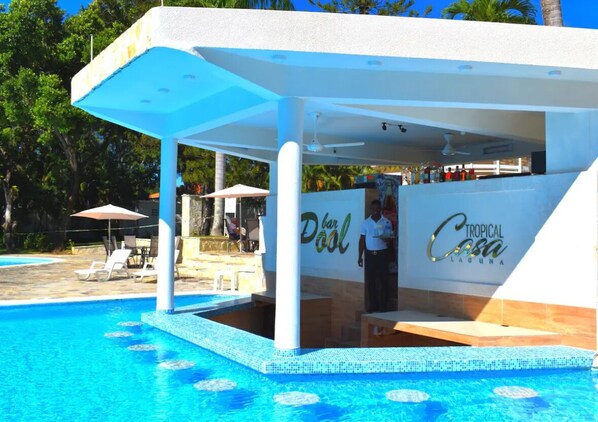 Un espace bar situé au bord de la piscine, avec une enseigne indiquant : « Dool Tropical Casa Laguna ».