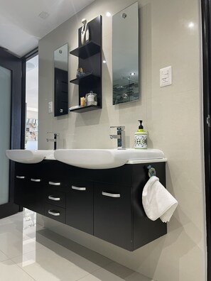 A modern bathroom with a dual sink vanity, a large mirror, and a towel rack. - Paradis - Luxurious Apartment with Ocean View and Balcony. (San Juan)