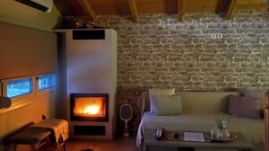 Une pièce chaleureuse avec un mur en pierre, une cheminée, un canapé et une petite table sur laquelle se trouve un plateau.