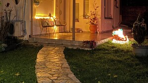 Une maison avec un chemin de pierre menant à un patio couvert, agrémenté de chaises et d’une table.