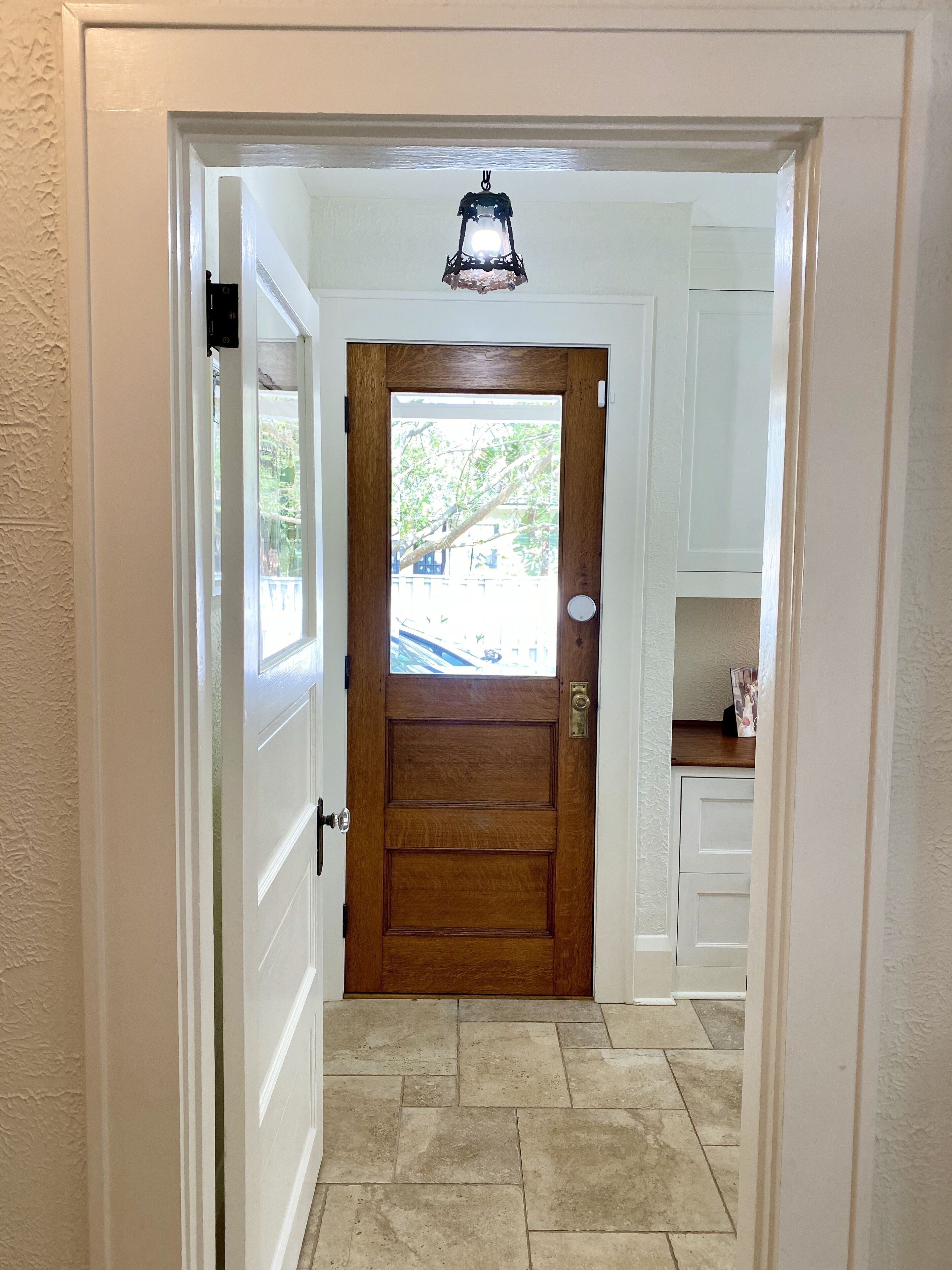 A hallway with a wooden door, a small window, and a light fixture above the door.