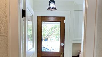 A hallway with a wooden door, a small window, and a light fixture above the door.