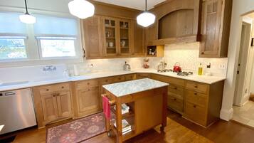 A kitchen with wooden cabinets, a marble countertop, and a small island with a sink.