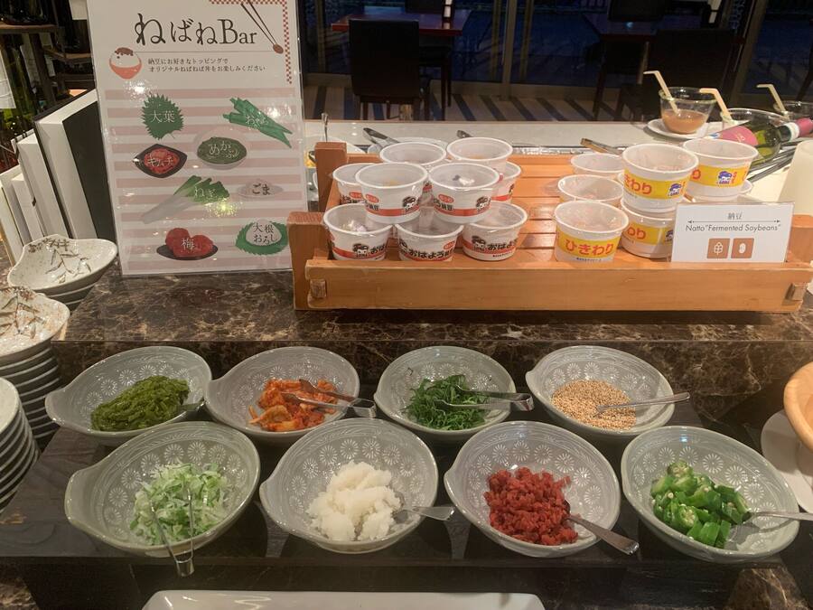 Disposição de buffet com diversos alimentos e recipientes para bebidas.