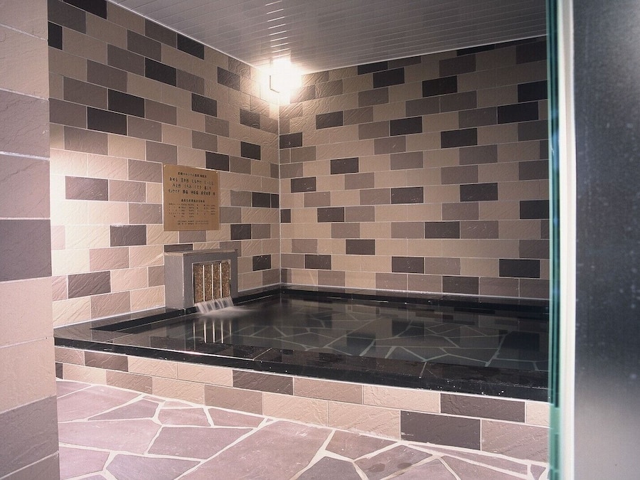 A spa area with a black marble countertop and a mosaic tile wall.