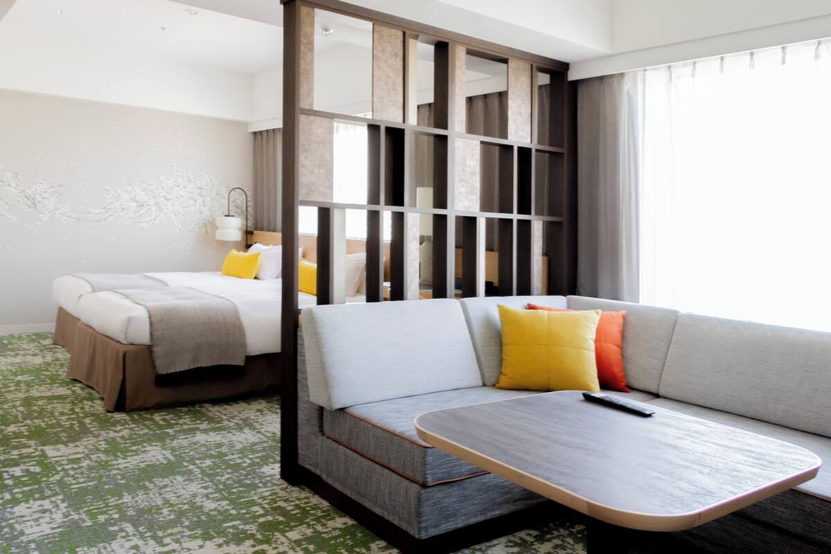Une chambre d’hôtel avec un lit, un canapé, une petite table et une cloison.