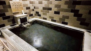 A hot spring bath with a tiled wall and a signboard. - Hotel Terrace The Garden Mito (Mito)