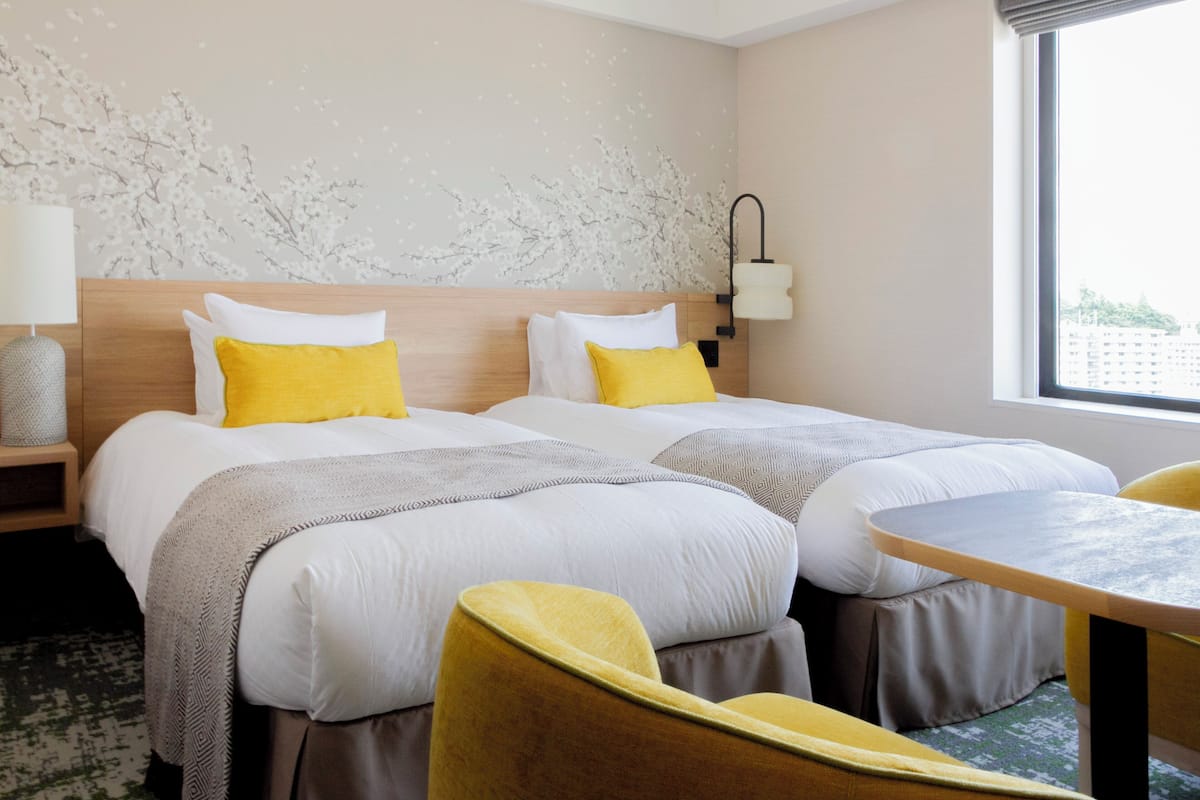 Une chambre d’hôtel avec deux lits, une petite table et une chaise.