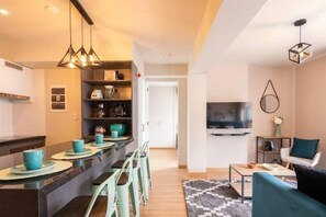 Relax in this stylish living space with a central island kitchen, sofa, and flat-screen TV.