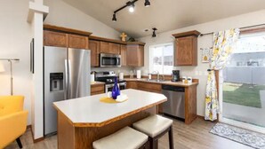 A modern kitchen with wooden cabinets, stainless steel appliances, and a central island with bar stools.