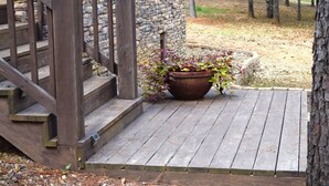 Un escalier en bois menant à un mur de pierre, une terrasse en bois et un bac à fleurs contenant des plantes.
