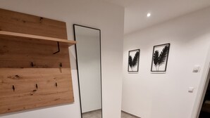 A modern room with a wooden bench, a large mirror, and two framed artworks on the wall.