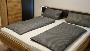 A modern bedroom with a wooden bed frame, two pillows, and a nightstand.