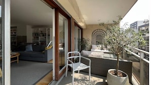 A balcony with a sofa, chairs, and potted plants.