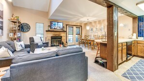 A spacious living room with a gray sofa, a fireplace, and a dining area with wooden chairs and a table. - Community Beach Access: Lake Harmony Townhome (Lake Harmony)