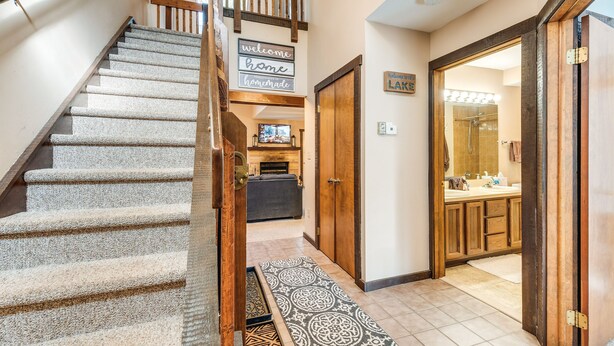 A staircase with a wooden handrail and carpeted steps leading to a living area with a fireplace. - Community Beach Access: Lake Harmony Townhome (Lake Harmony)