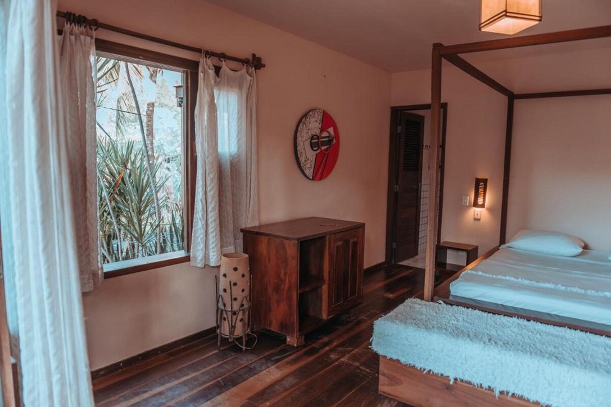 Une pièce comprenant un lit, une armoire en bois, une horloge ronde fixée au mur et une fenêtre avec des rideaux.