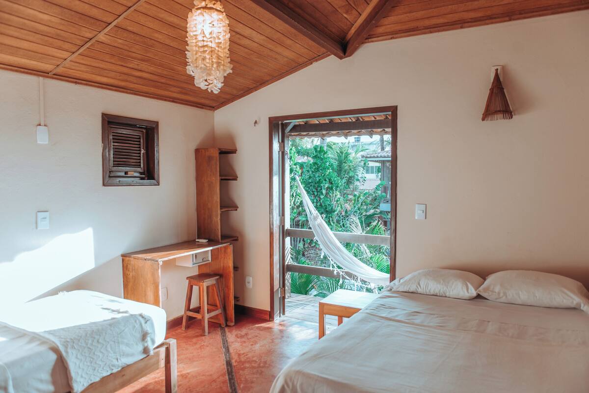 Una habitación con escritorio de madera, cama y hamaca.