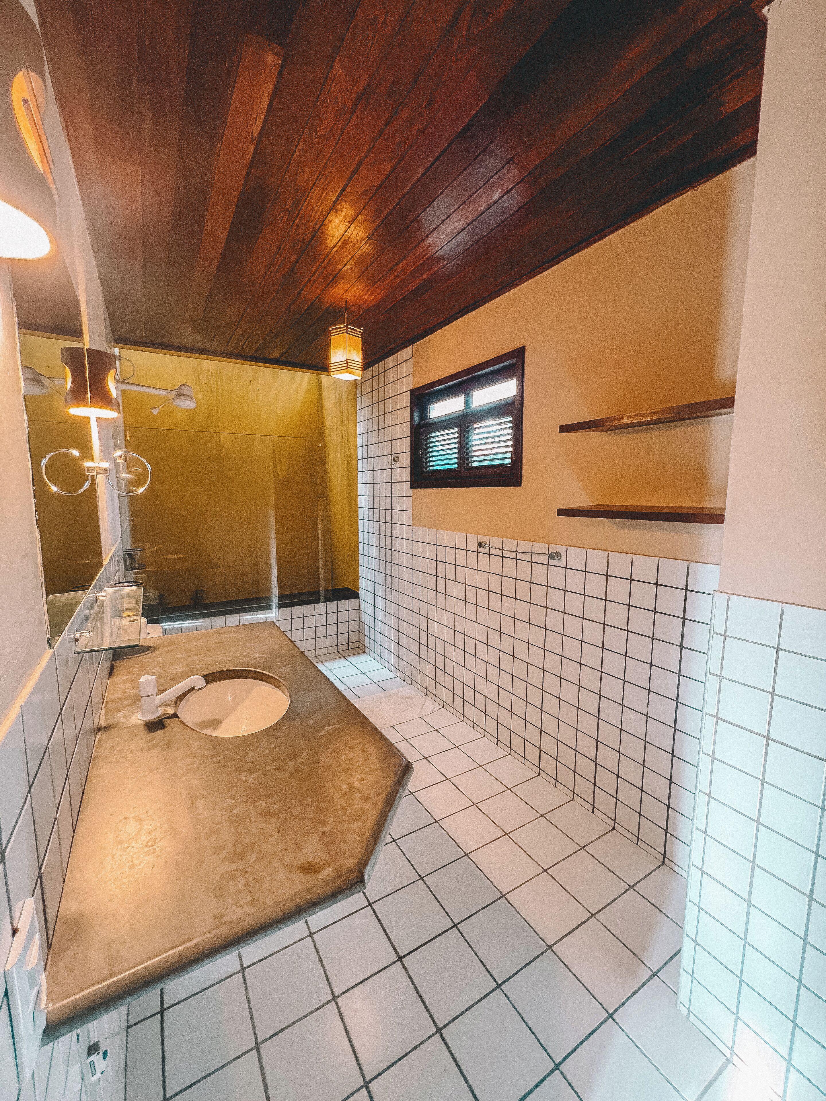 Un baño con techo de madera, un inodoro, un lavamanos y una ventana.