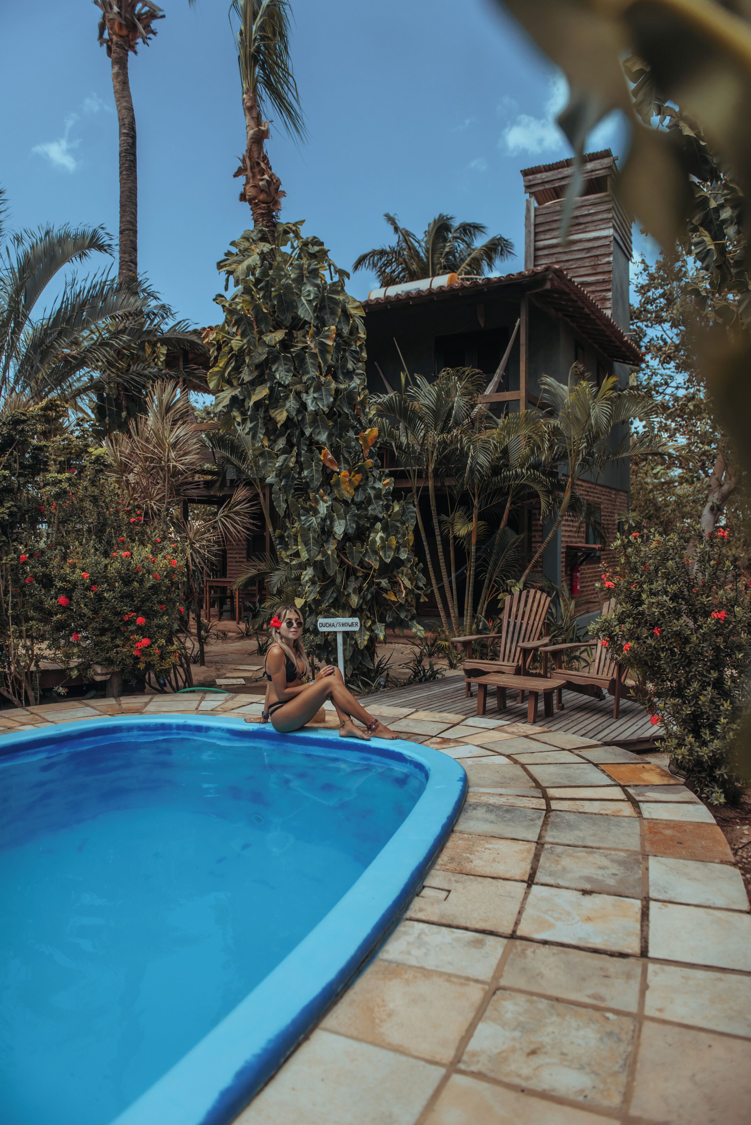 A pool area with a tiled deck, wooden chairs, and a sign indicating a private area.