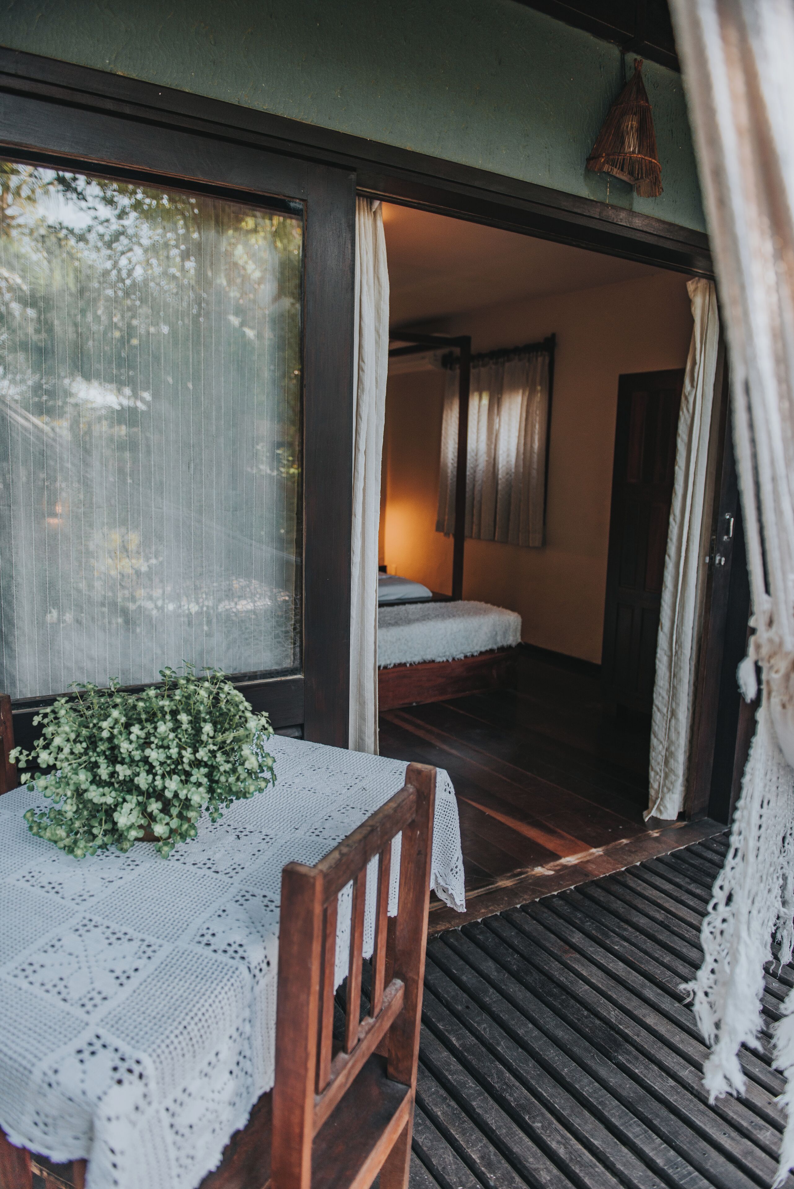 Una habitación acogedora con una cama, una mesa con mantel de encaje y una pequeña planta.