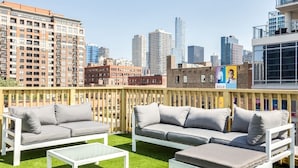 An outdoor seating area with white furniture and a city skyline view.