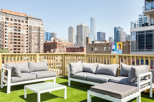 An outdoor seating area with white furniture and a city skyline view. - The Orleans Floor 3 Private rooftop deck! (Chicago)