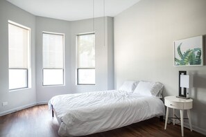 A bedroom with a bed, a bedside table, and three windows. - The Orleans Floor 3 Private rooftop deck! (Chicago)