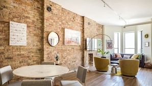 A spacious living area with a brick wall, round table, and modern furniture.