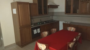 A compact kitchen with wooden cabinets, a built-in oven, and a dining area with a red table and chairs. - "\"little Prince\" 18km From Padua 30km From Chioggia" (Brugine)