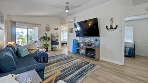A living room with a sofa, coffee table, TV, and a large window. - Cozy 2-bedroom condo with WiFi, AC in peaceful Oceanside (Oceanside)