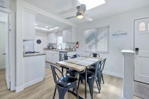 Una cucina moderna con mobili bianchi, un tavolo da pranzo con sedie nere e una ventola a soffitto.