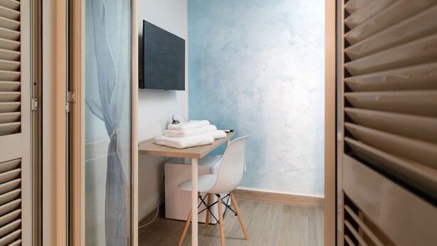 A room with a desk, chair, and a wall-mounted TV. - GG - Grow - Terrazza di Bellavista (Naples)