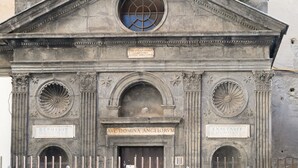 A historic building facade with classical architectural elements, including a central archway, decorative moldings, and inscriptions on plaques. - GG - Grow - Terrazza di Bellavista (Naples)