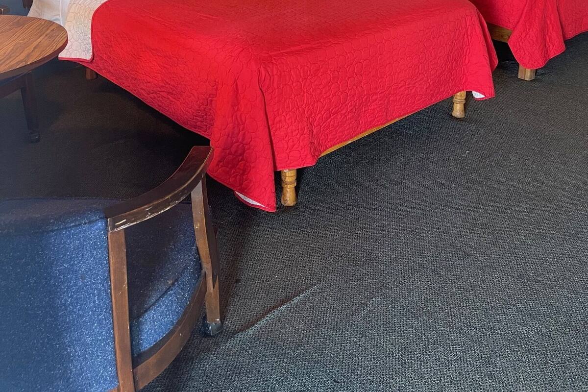 A hotel room with two beds, a small table, and a lamp.