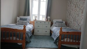 Un dormitorio con dos camas individuales, un aparador y una ventana con cortinas.