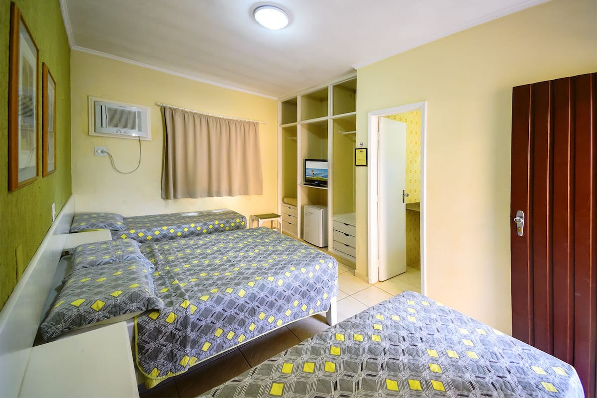 Ein Zimmer mit zwei Betten, einem Fernseher, einem Kleiderschrank und einem Badezimmer.