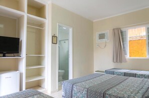 A bedroom with a bed, a television, a wardrobe, and a bathroom visible through an open door. - Pousada do Sol (Ubatuba)